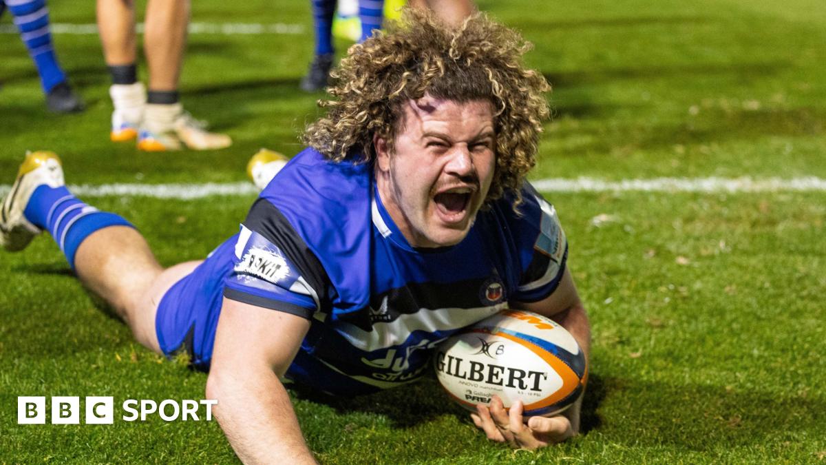 Alfie Barbeary slides on the grass over the tryline with the ball tucked under his body held in his left arm, with his right arm stretched onto the floor in front of him