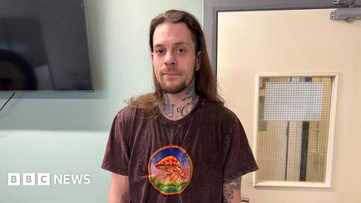 Curtis DuRose, a man with long brown hair, a beard and a brown t-shirt with red toadstools on it.