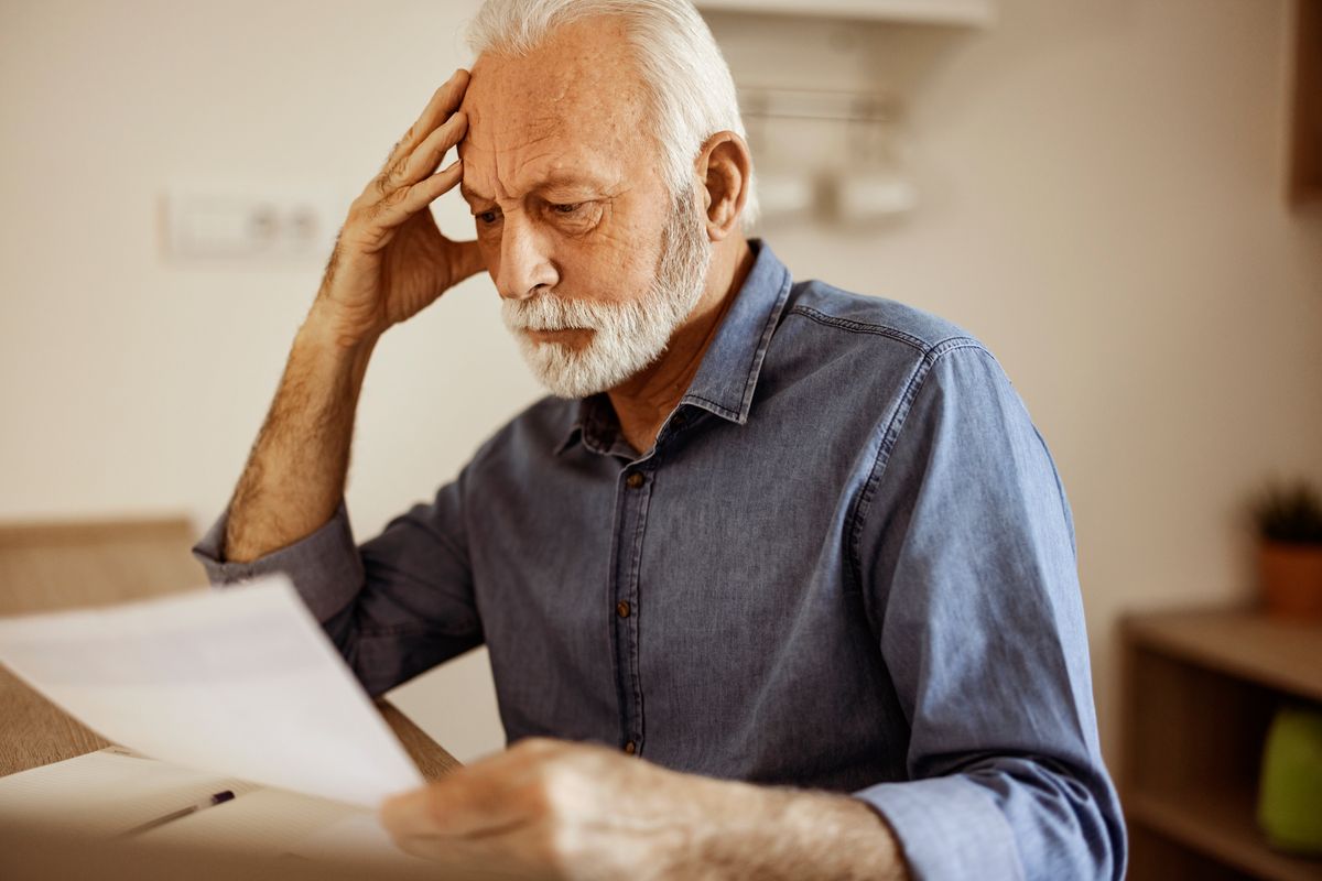 Worried senior man analyzing home finances in the kitchen