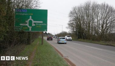 A38 motorway with cars on the road, with a grass verge to the left and a sign saying Birmingham A38 with directions to M6 toll, Brownhills (A5), Burton and Derby (A38)