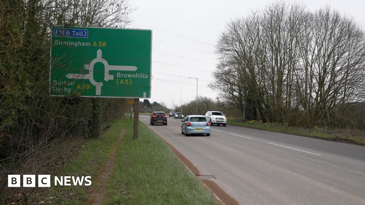 A38 motorway with cars on the road, with a grass verge to the left and a sign saying Birmingham A38 with directions to M6 toll, Brownhills (A5), Burton and Derby (A38)