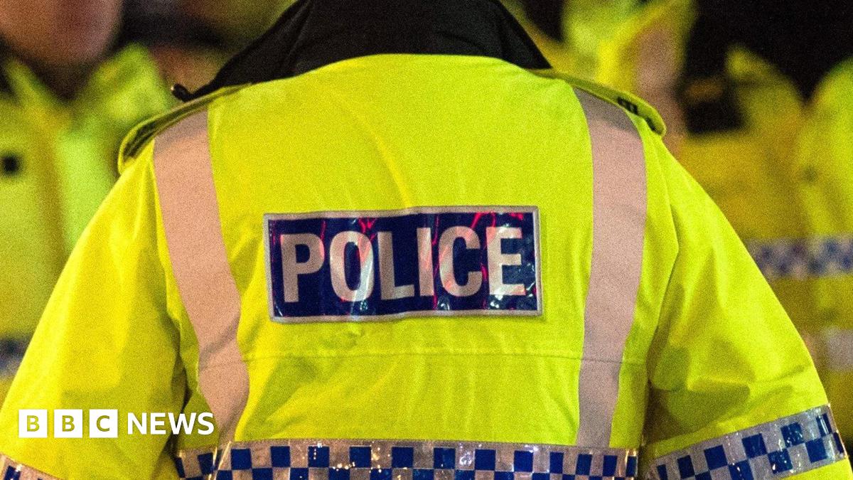Generic image of a police officer in Greater Manchester, wearing a hi-vis yellow jacket with police labelled on the back.