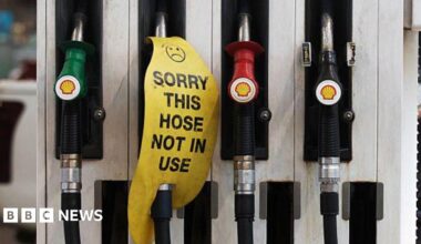 Petrol dispensers at a petrol station. One has a sign reading "sorry this hose is not in use".