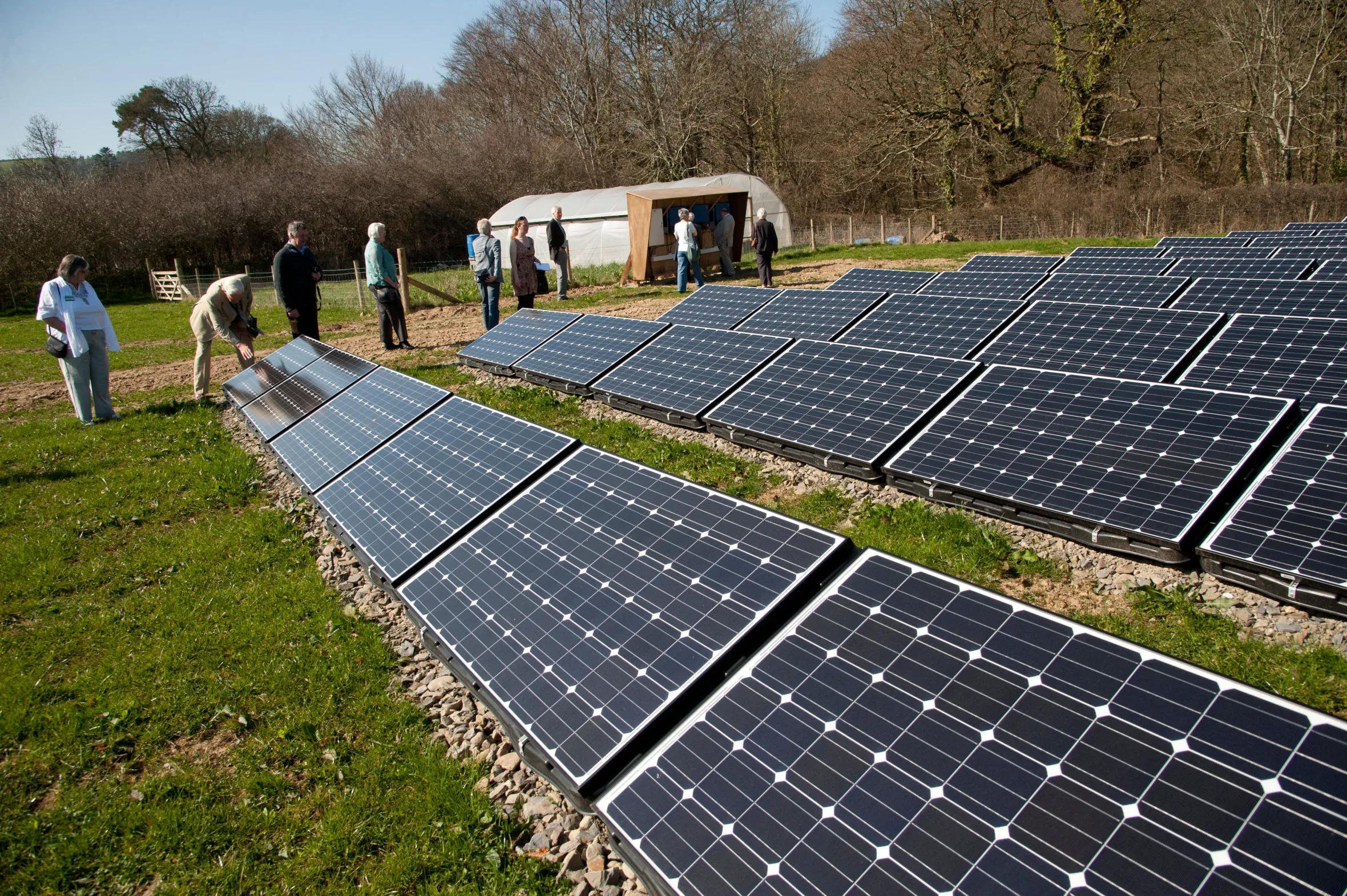 People look at photovoltaic cells in an array at Llanerchaeron, Wales, UK.