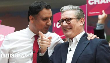 Anas Sarwar standing next to Sir Keir Starmer at a Labour Party event. Sarwar is wearing a white shirt and red tie and has his hand on the shoulder of Starmer, who is wearing a white shirt, a blue jacket and black-rimmed glasses.