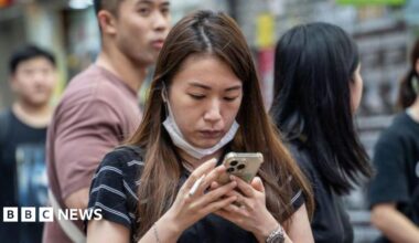 A woman holding a cigarette and looking at her phone in Hong Kong, China, on June 6, 2024