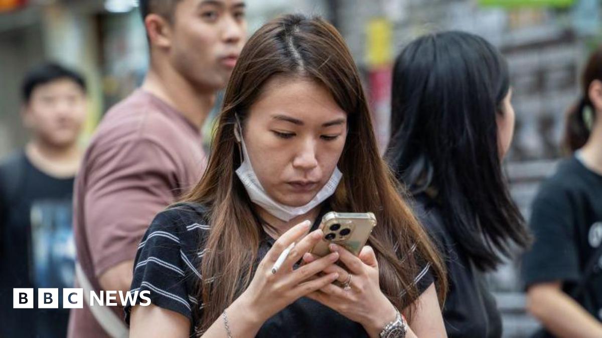 A woman holding a cigarette and looking at her phone in Hong Kong, China, on June 6, 2024