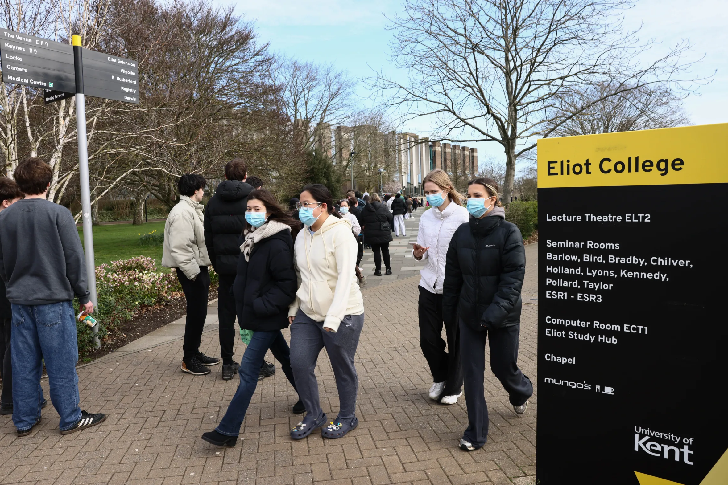 Students wearing facemasks queuing to receive antibiotics at Kent University.