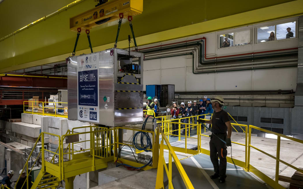 A specially designed portable cryogenic Penning trap device filled with a cloud of 92 antiprotons is transferred onto a truck during a successful test drive of the world’s first antimatter delivery system, conducted by CERN’s BASE-STEP experiment, which transported antiprotons by road across the organization’s main site, in Meyrin near Geneva, on March 24, 2026. The ultimate goal is to transport antiprotons to facilities such as Heinrich Heine University in Dusseldorf, where a calmer magnetic environment would enable measurements with greater precision. Such advances could provide crucial insights into one of the fundamental questions of physics: why matter dominates over antimatter in the universe. (Photo by Fabrice COFFRINI / AFP)