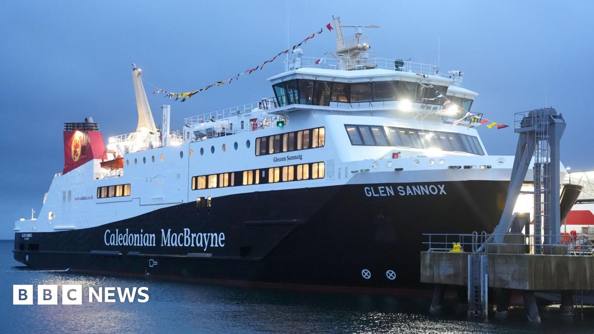 The MV Glen Sannox, a large black and white ferry with a red hull docked at a pier.
