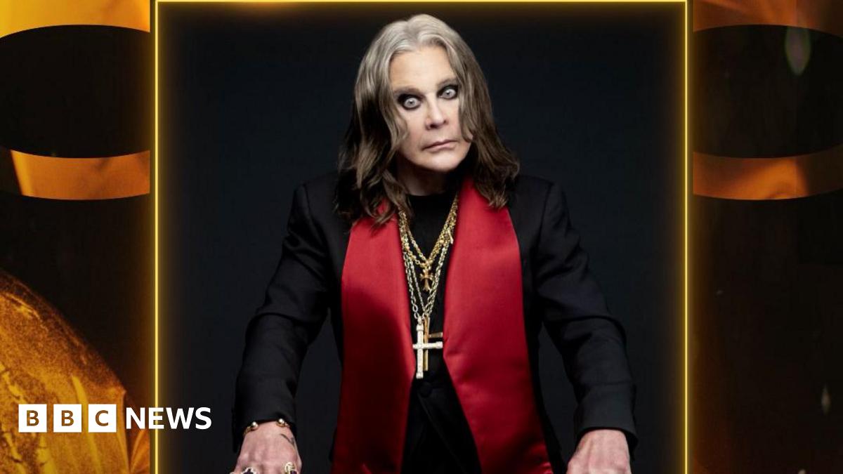 A photo of Ozzy Osbourne wearing a black jacket with large red lapels and several gold chains with crosses around his neck. He looks intensely at the camera.