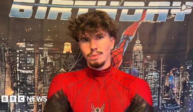 A young man in a red and black superhero costume.