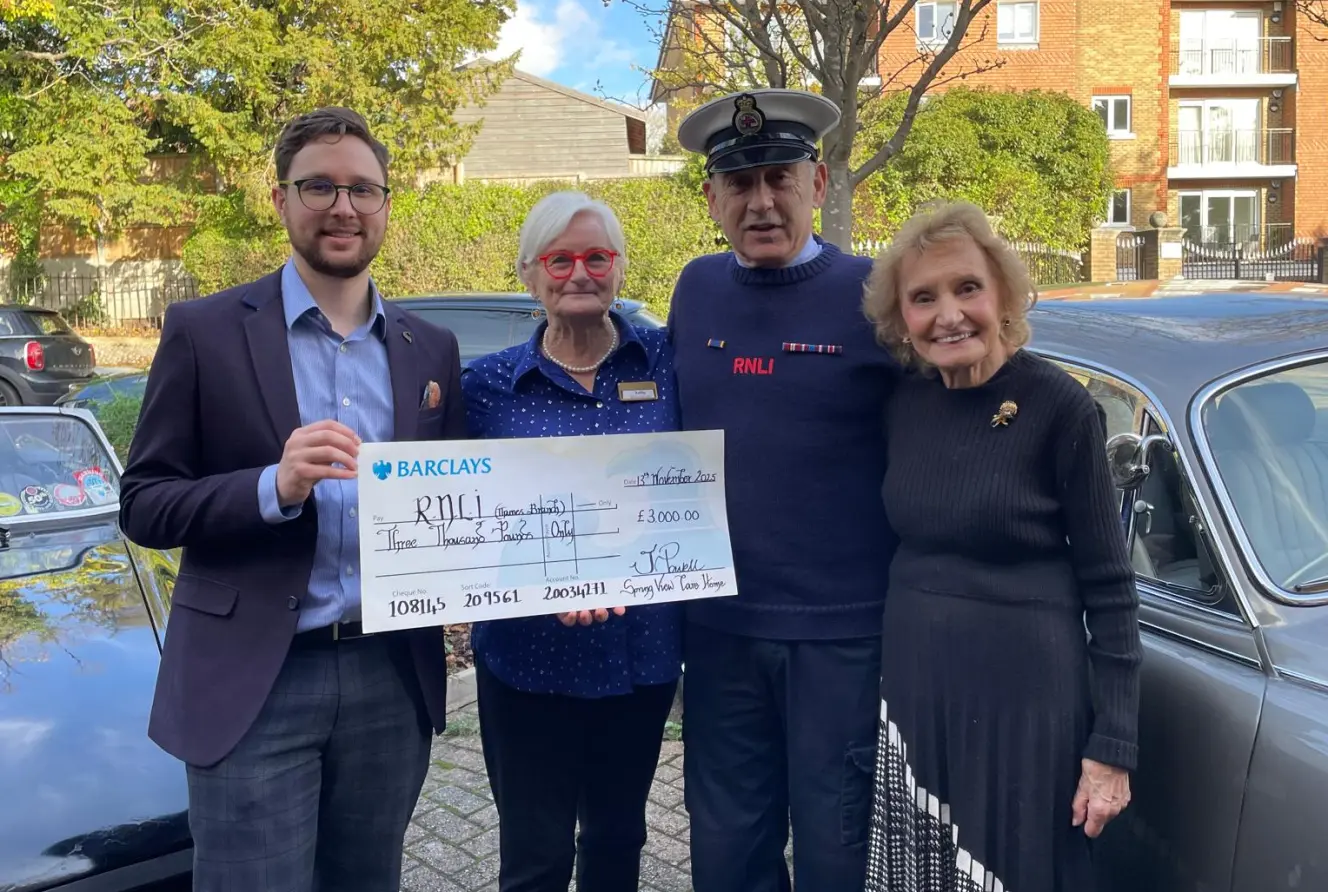 Four people holding a large check for £3,000 to the RNLI.