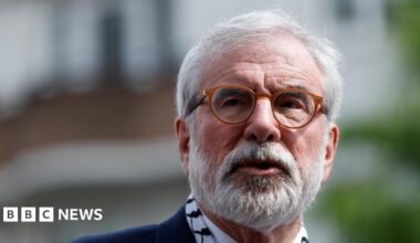 A man with a white beard and brown rimmed glasses looks off camera. All that is visible is his face - it is an up close picture.