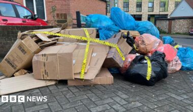 A large pile of rubbish and cardboard boxes on the side of a street.