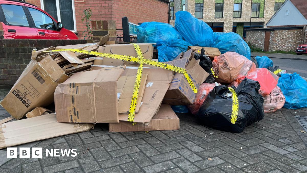 A large pile of rubbish and cardboard boxes on the side of a street.