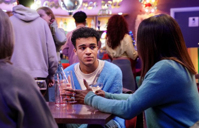 Josh sitting at a table in The Albert bar in EastEnders.