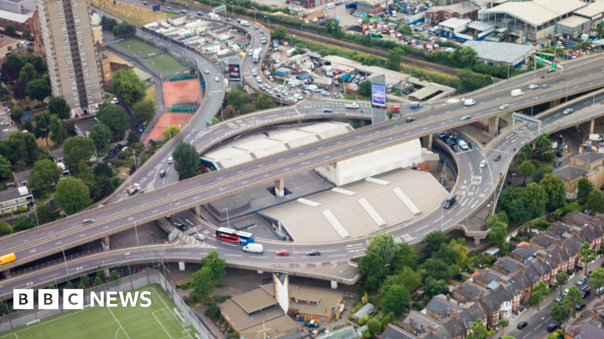An ariel shot of the A40 showing small cars and London buses as well as surrounding houses and greenery.