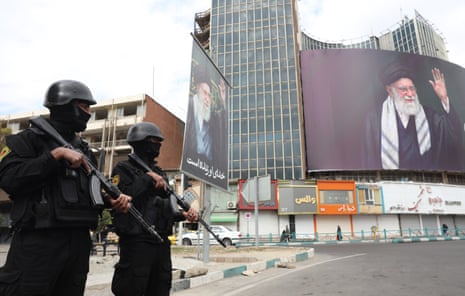 Iranian security forces stand guard next to the huge billboard of the late Iranian Supreme Leader Ayatollah Ali Khamenei at Valiasr Square in Tehran, Iran.