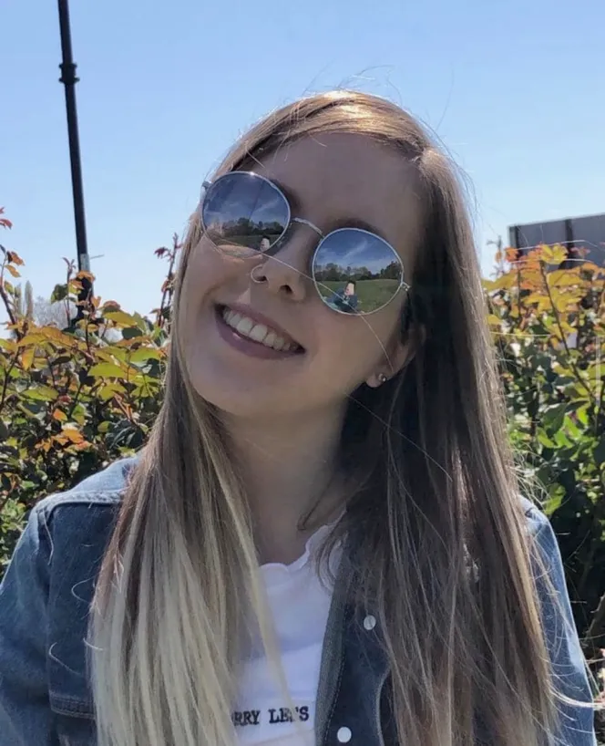 Zara Taylor wearing round sunglasses and a denim jacket.