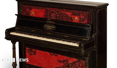 An upright piano in dark wood, with a red and black design on the front.