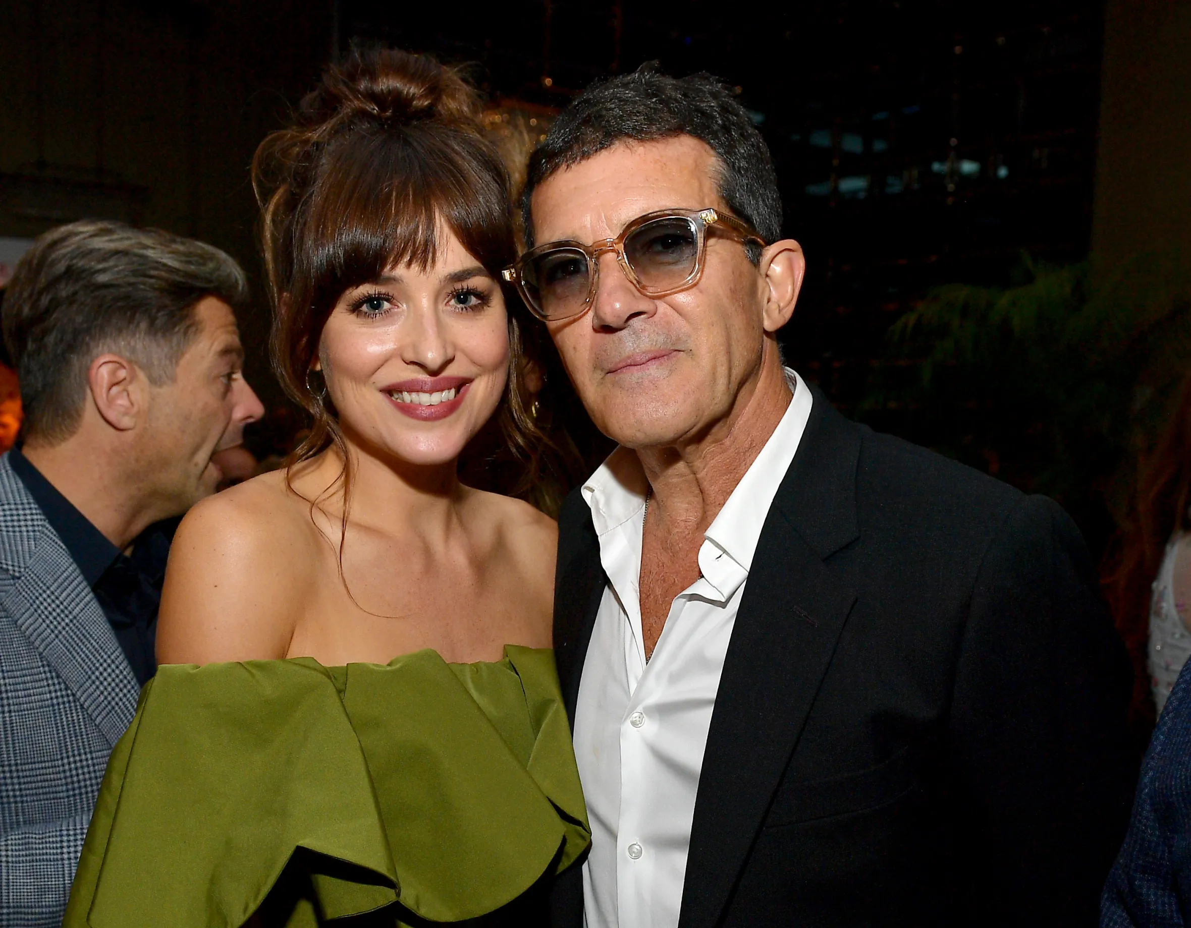 Dakota Johnson in a green dress and Antonio Banderas in a suit and sunglasses.