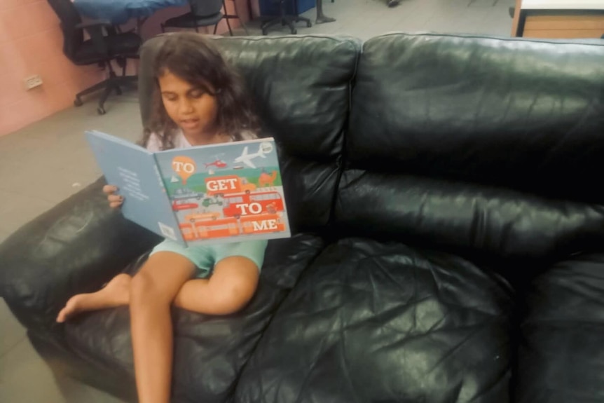 Young girl on couch reading book