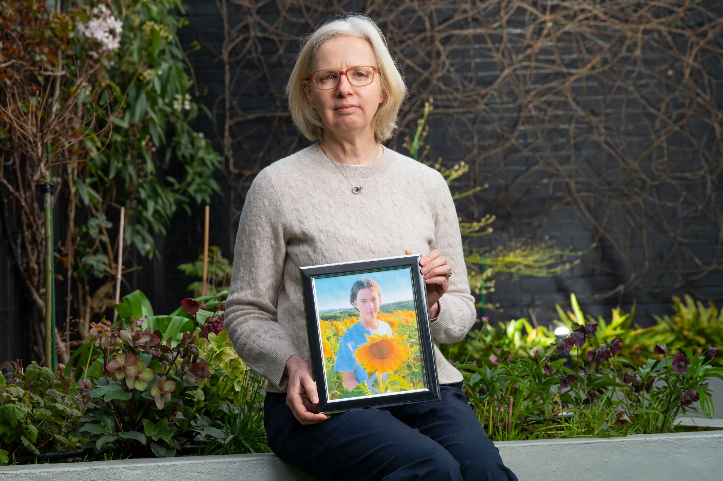 Sophie Boucher, Arthur's aunt, holding a framed photo of Arthur in a field of sunflowers.