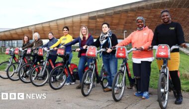 Eight women each holding a Santander TFL hire bike, which has been named after them for being an inspirational women in the cycling community. The women are all smiling