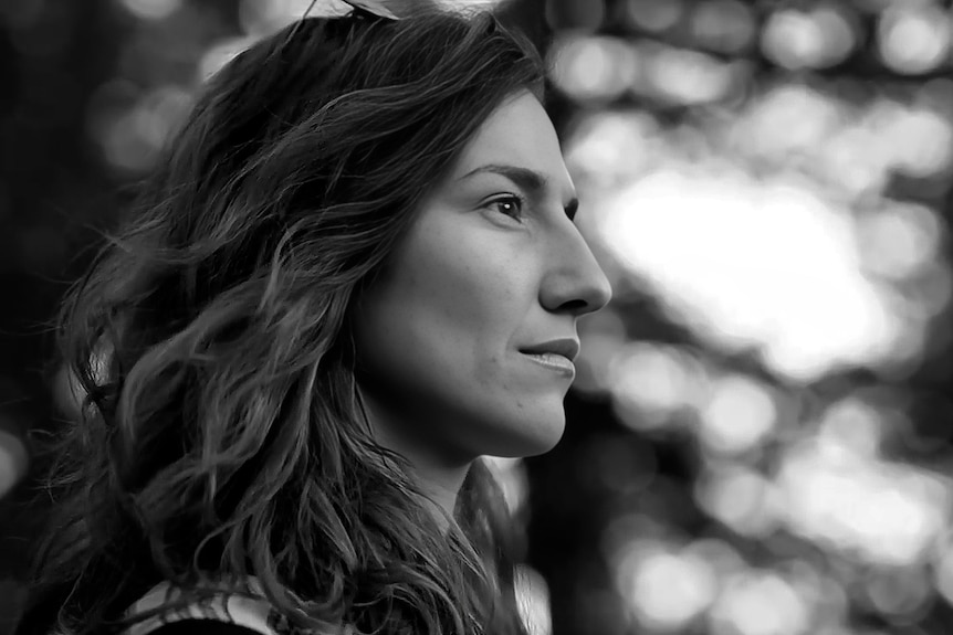A black-and-white photo of a woman with flowing dark hair looks off to the right in contemplation.