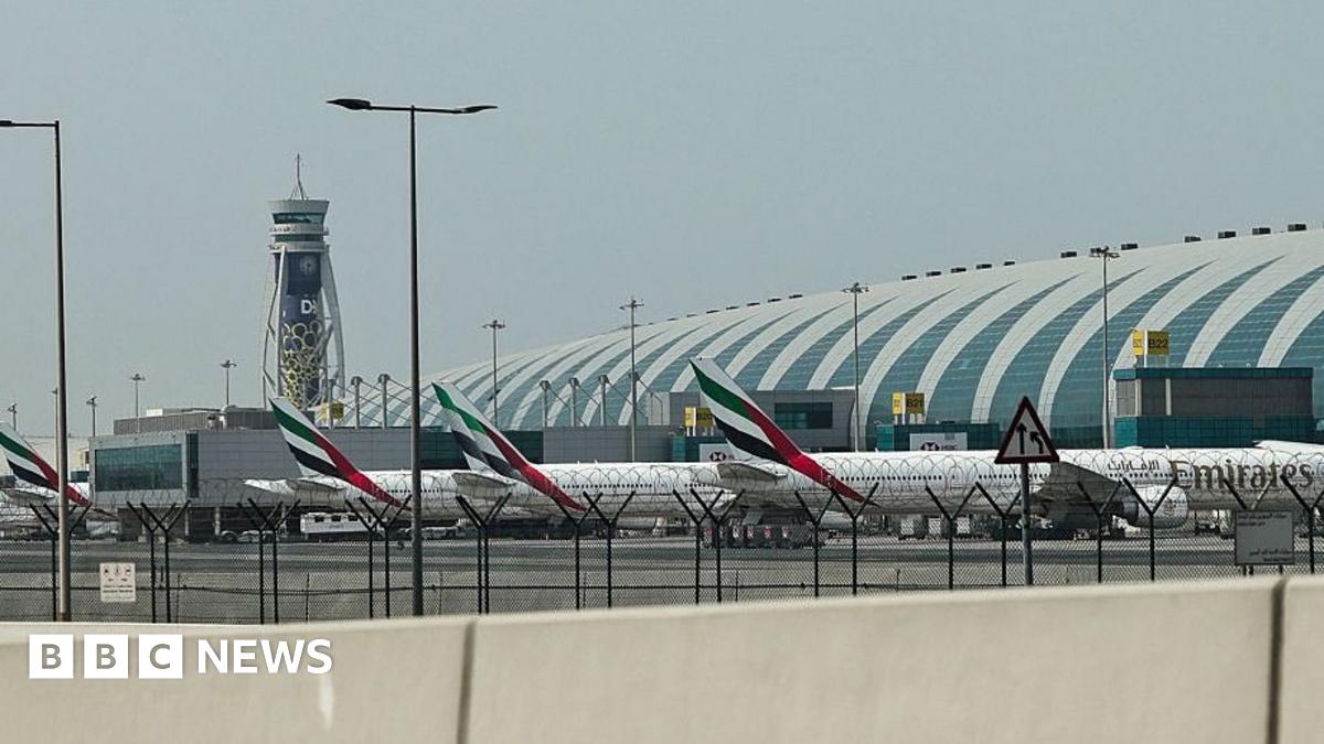 Three Emirates planes lined up at Dubai International Airport, a control tower stands in the background.