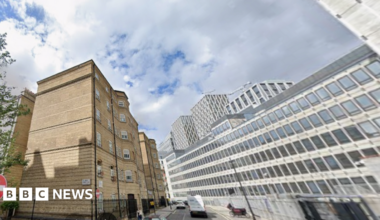 General view of Abbey Orchard Street showing cars on the road, a brown brick building to one side and a large office block to the other.