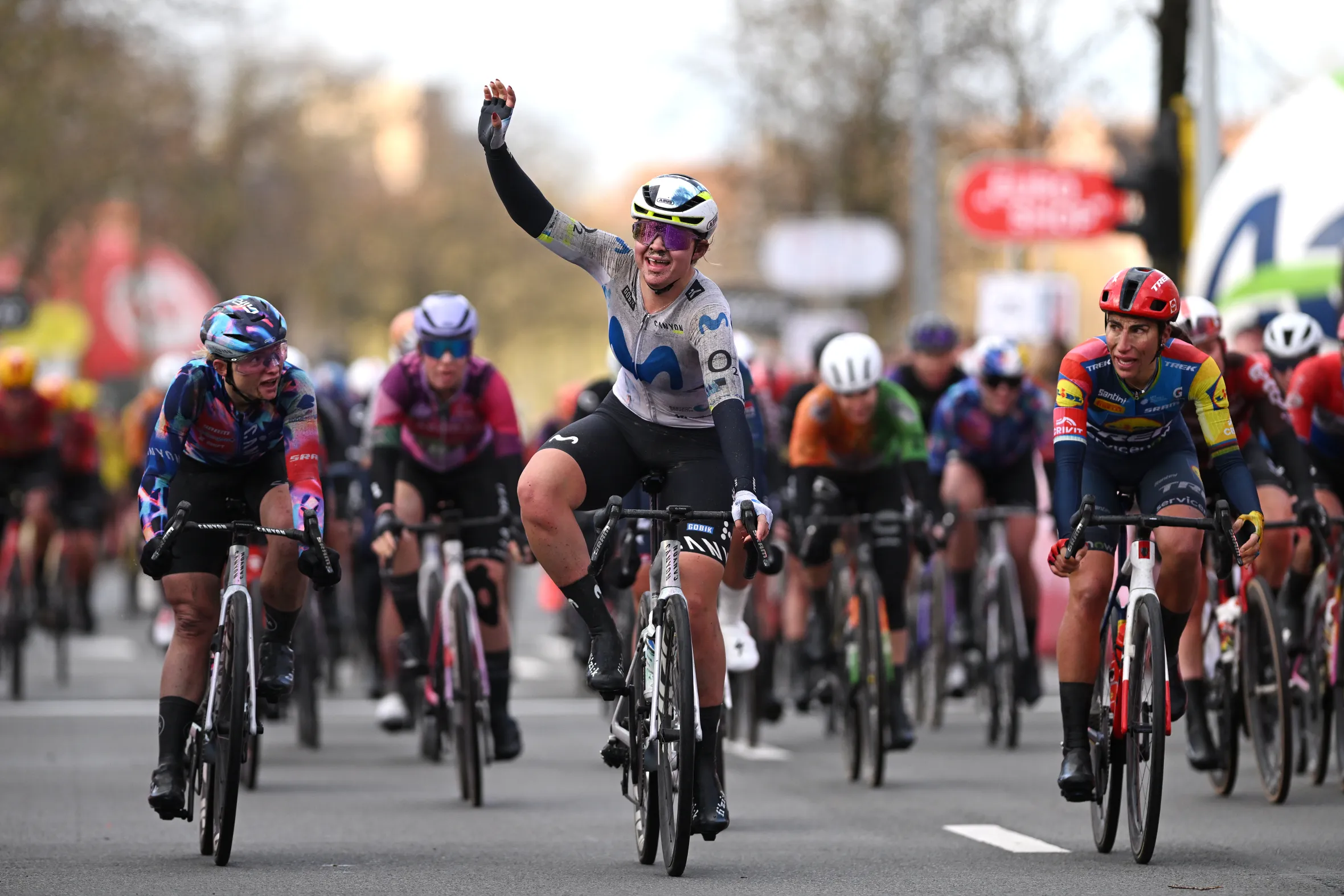 Carys Lloyd celebrating victory on her bike at the finish line ahead of Chiara Consonni and Elisa Balsamo during the 9th Ronde van Brugge - Tour of Bruges 2026.