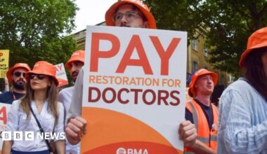 A person at a strike holds a poster which reads: "Pay restoration for doctors."