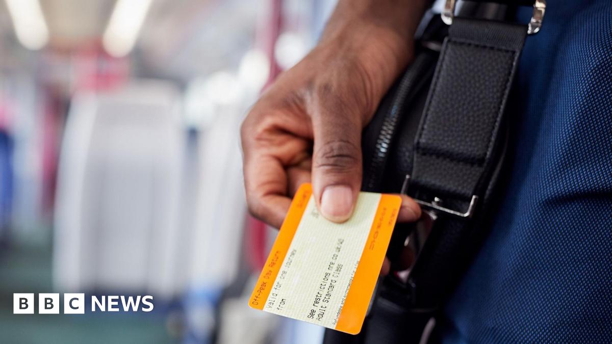 A hand holds a UK rail ticket.
