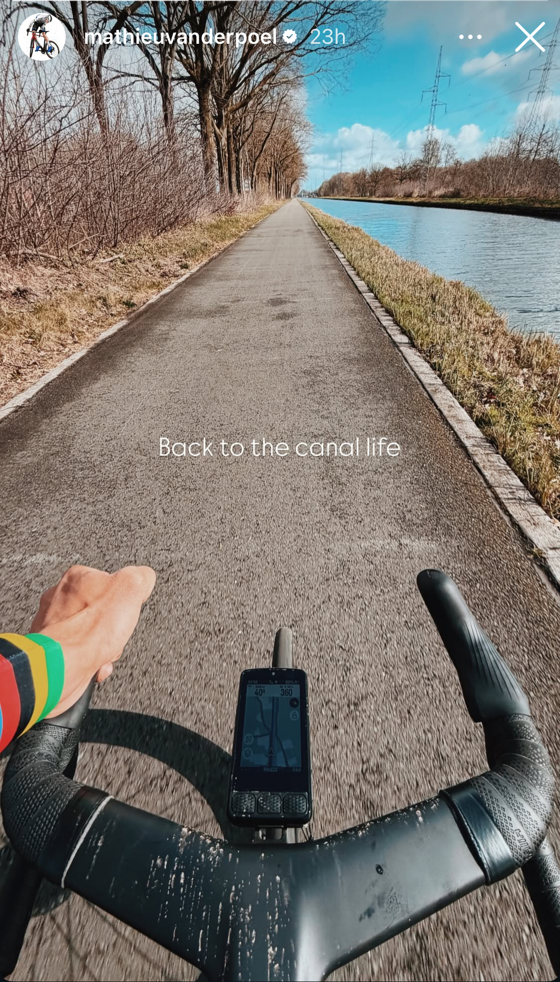 A picture of a pair of carbon fibre handlebars on Mathieu van der Poel's bike as he cycles down a canal