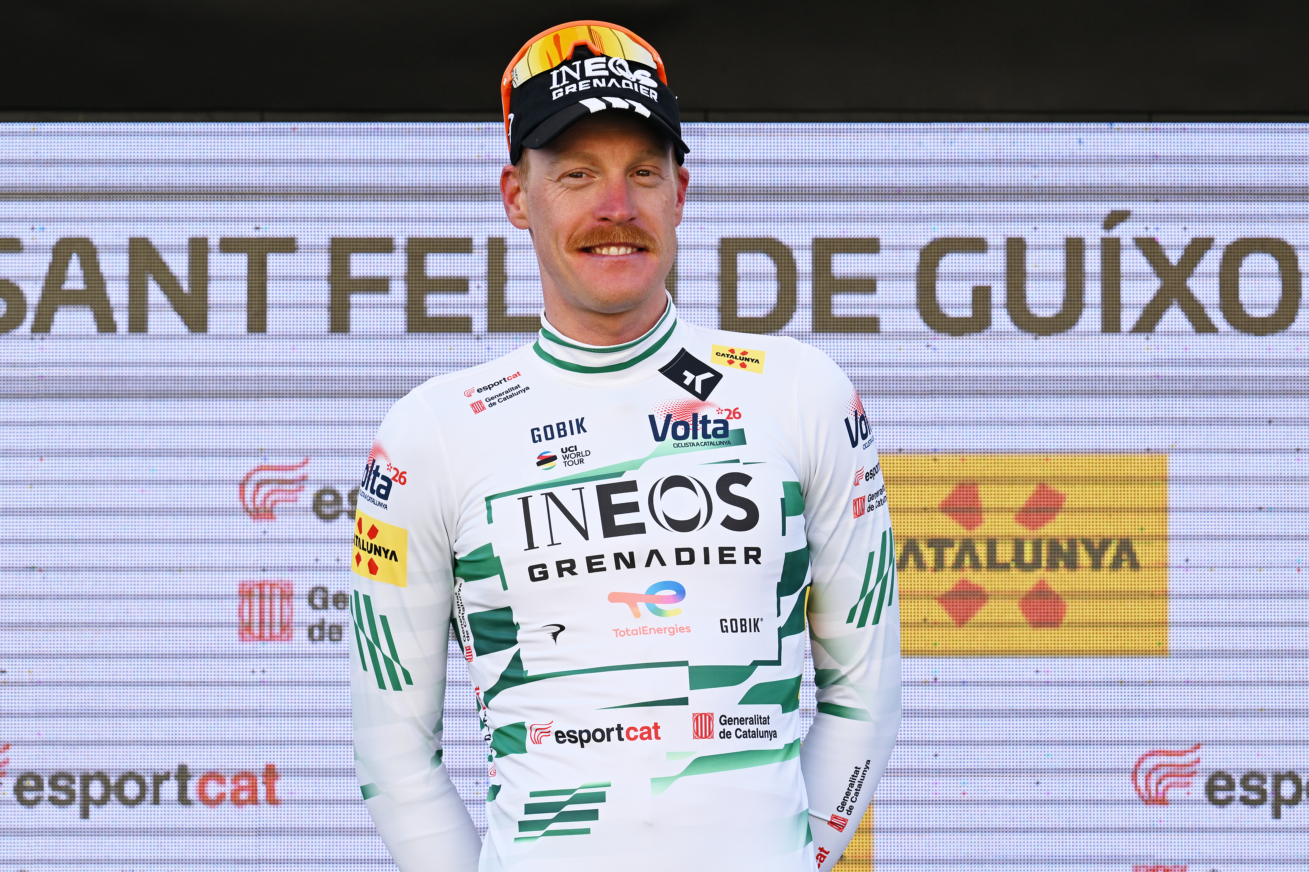 Dorian Godon on the podium at the Volta a Catalunya wearing the white and dark green leader's jersey after winning stage 1 of the 2026 race.