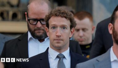 Mark Zuckerberg walking down the grey stone steps of a Los Angeles court house wearing a navy suit blazer, grey neck tie and white shirt.