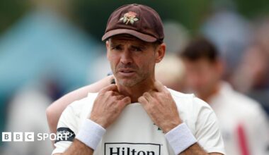 Ajeet Singh Dale has his body almost bent double through the exertion of bowling fast. He is also wearing a black watch on his left arm and he has a headband to keep his black flowing hair in check.