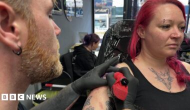 A woman with pink hair having a tattoo done.