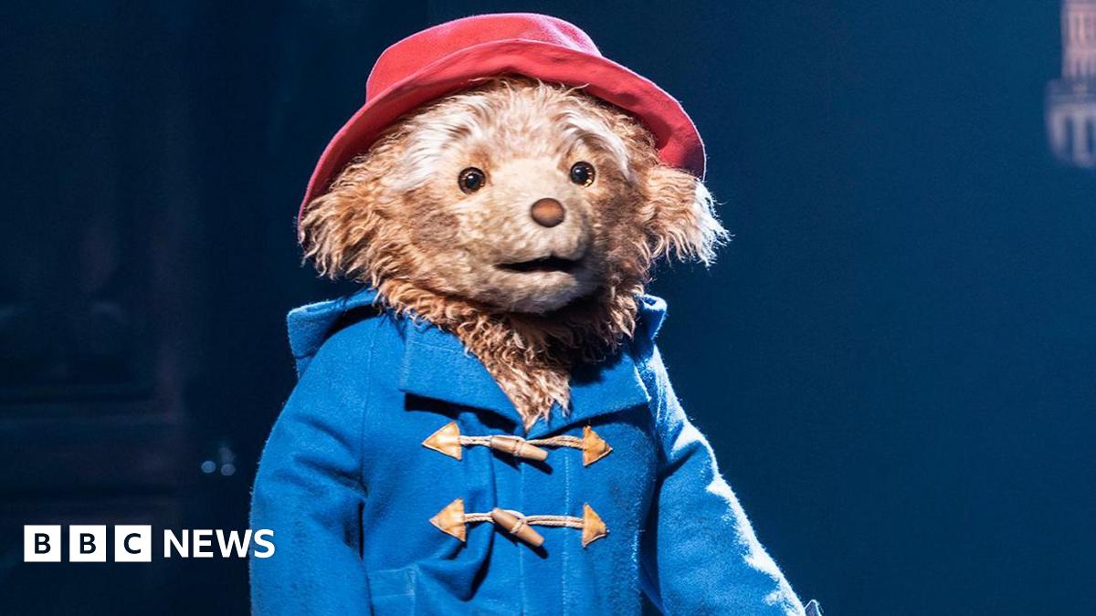 Paddington Bear on stage in Paddington The Musical, wearing a blue jacket