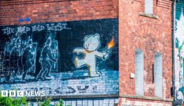 The famous Banksy art work 'The Mild Mild West' at Stokes Croft. It shows a large mural on the side of a red-brick building, depicting a bear throwing a Molotov cocktail at a group of police officers behind plastic shields.