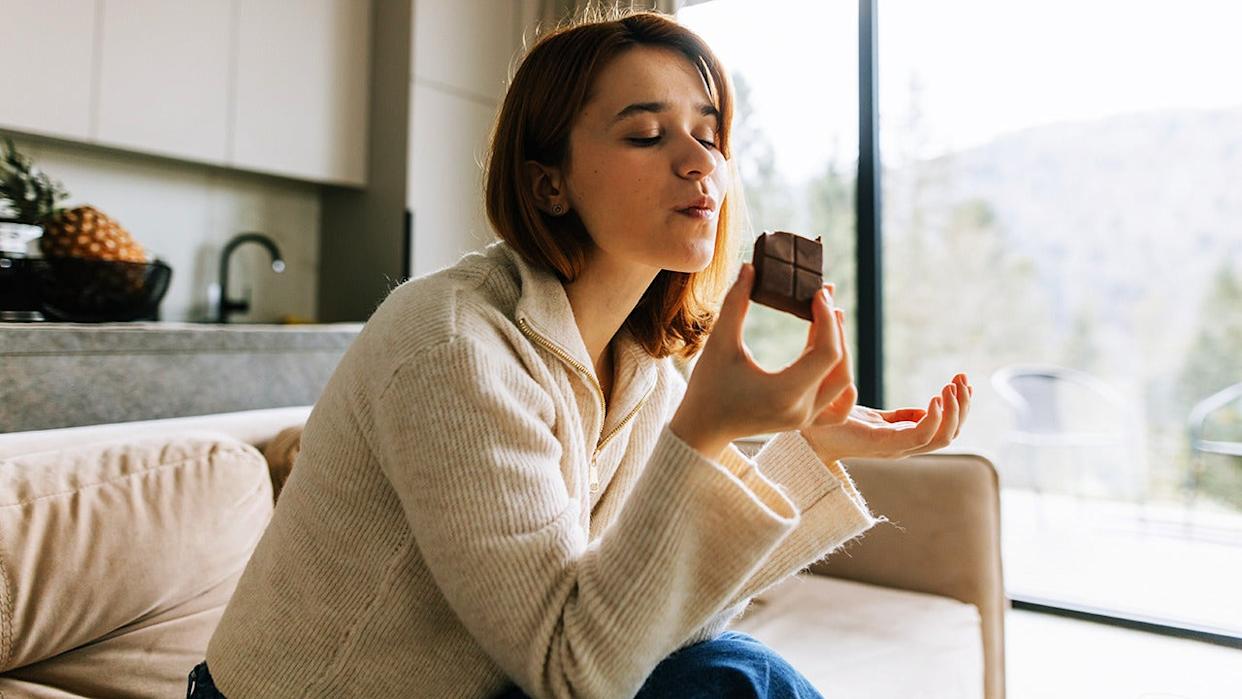 Woman enjoying chocolate on couch.