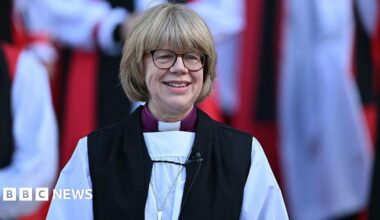 The new Archbishop of Canterbury Sarah Mullally smiles on the steps of St Paul's Cathedral after taking part in a Confirmation of Election ceremony in London on January 28, 2026. She is wearing church gowns.
