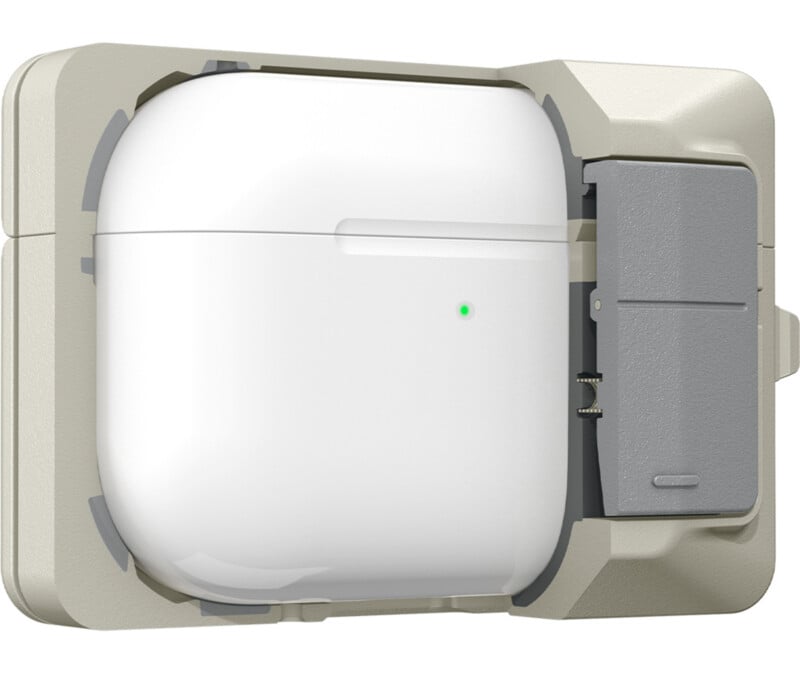 A white wireless earbud charging case with a green LED light is secured in a beige wall-mounted holder, which includes a gray sliding compartment on the right side.