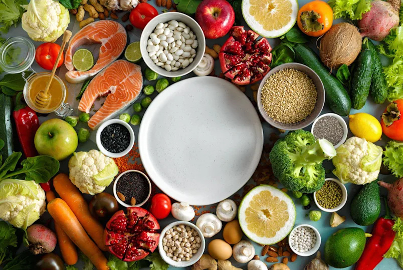 Healthy balanced diet ingredients surrounding a white empty plate