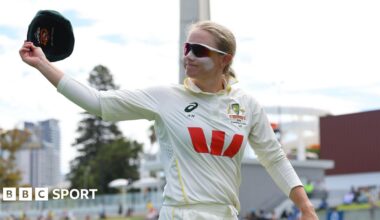 Australia captain Alyssa Healy raises her cap in the air as she walks off the field