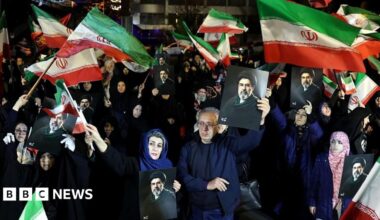 Iranians wave national flags and hold photos of the country's new Supreme Leader Mojtaba Khamenei at a rally in Tehran