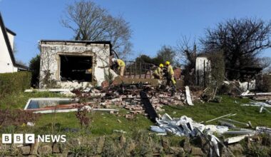 Firefighters view debris in a rural garden after the blast