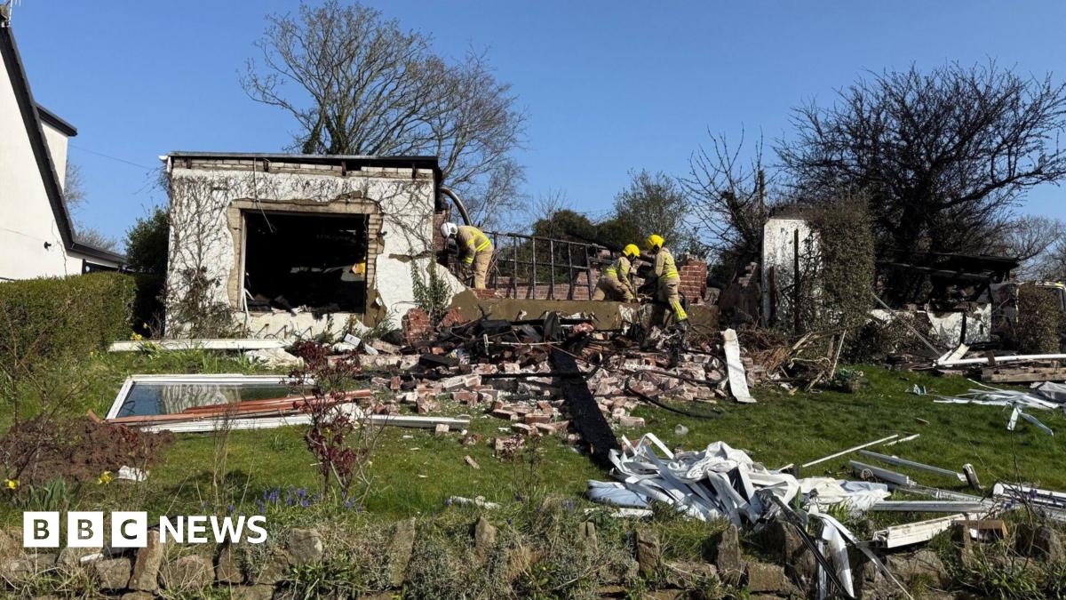 Firefighters view debris in a rural garden after the blast